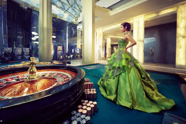 A woman in a luxurious green gown next to an ornate roulette wheel, capturing the upscale casino mood of 26JLPH.
